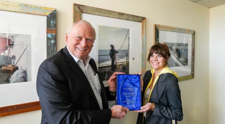 Eric Boerwinkle, PhD, dean of UTHealth Houston School of Public Health (left) presents Shannon Guillot-Wright, association professor (right) the Palmer Beasley Award