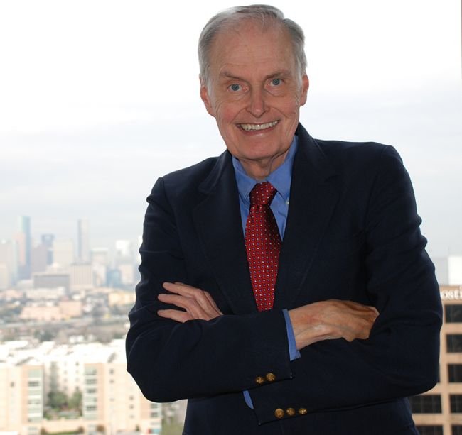 A man standing in front of a window overlooking a city