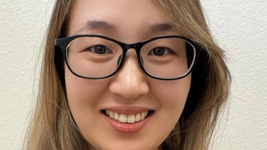 Jingjing Gao, PhD, smiling at camera wearing glasses and a maroon collard shirt.